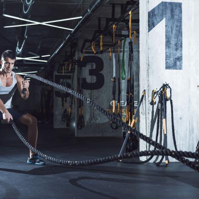 Young Man Exercising With Battle Ropes